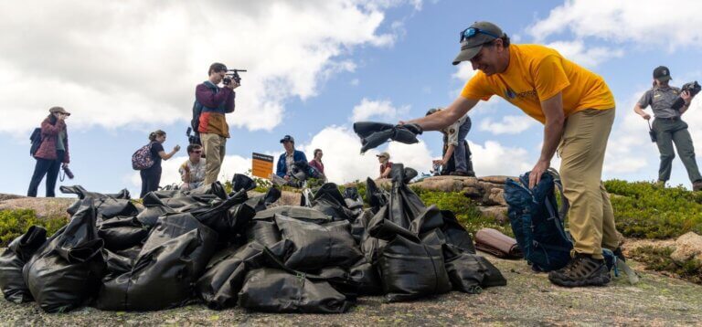 Un climatologue du Schoodic Institute dépose un sac de terre au sommet du mont Sargent lors de la randonnée Save our Summits. (Photo : Sam Mallon/Friends of Acadia)